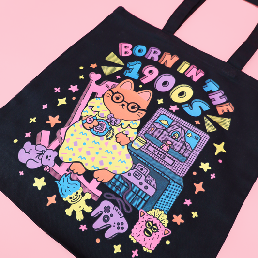 photo of a tote bag with the phrase, "born in the 1900s" featuring a cute old lady cat sitting on her rocking chair surrounded by her favorite millennial nostalgia. 