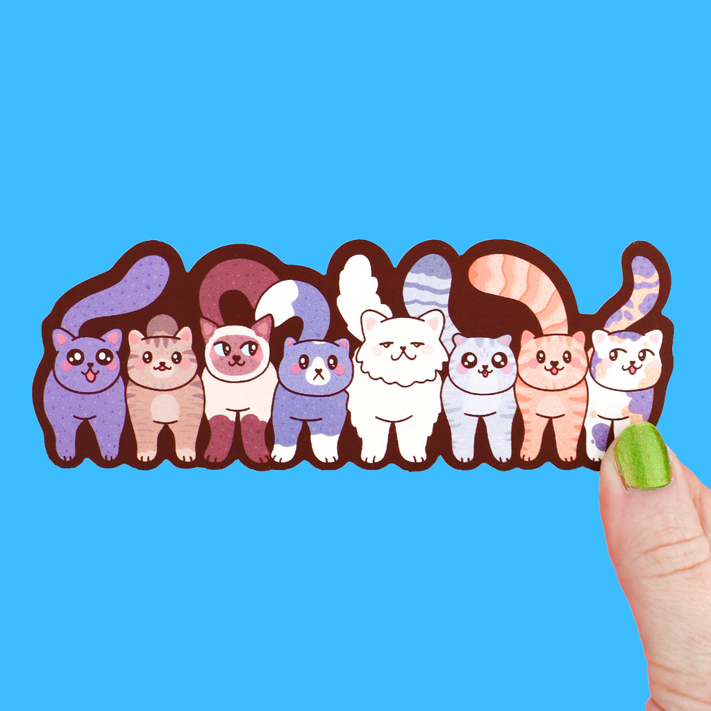 A long bookmark featuring a group of cats standing together in a row, they are many shapes and colors of cats