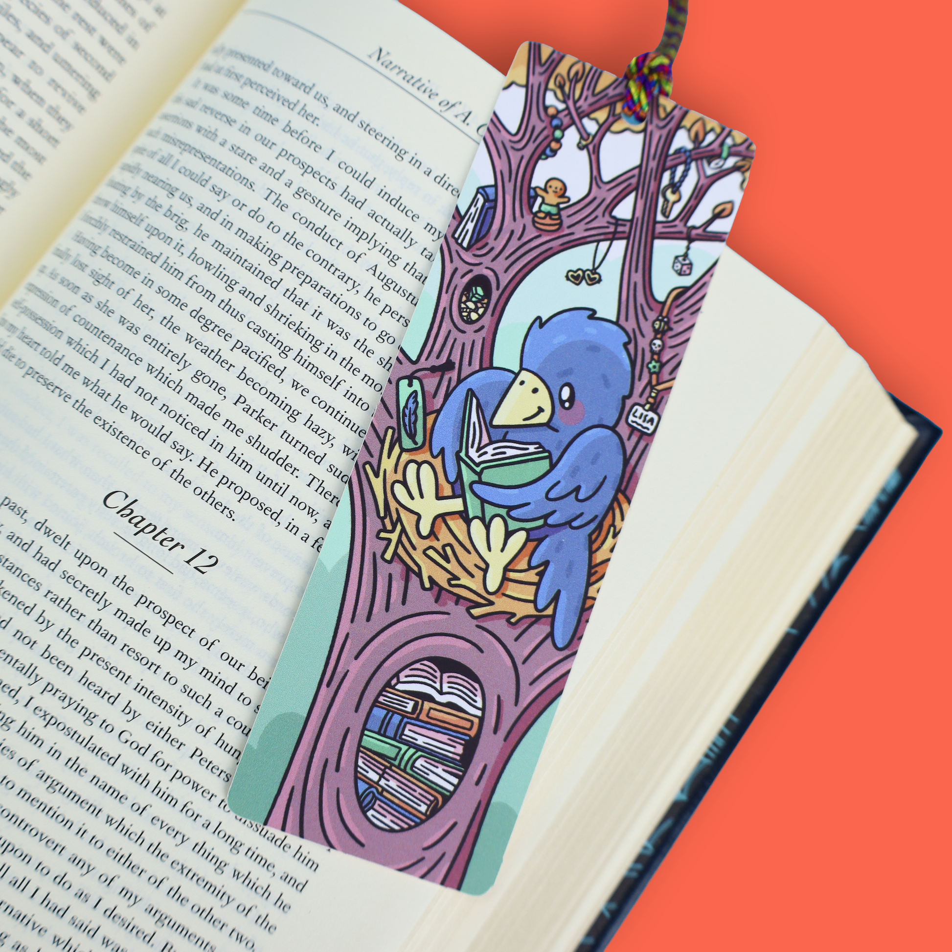 A colorful illustrated bookmark shaped like a tree trunk and birdhouse, placed across an open book on an orange background. The bookmark features a blue bird holding a green bowl, with shelves, books, and small whimsical details.