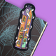 A Halloween-themed bookmark shaped like a haunted house, featuring cartoon ghosts and a purple cat, placed on an open book with a spiderweb pattern against a solid purple background.