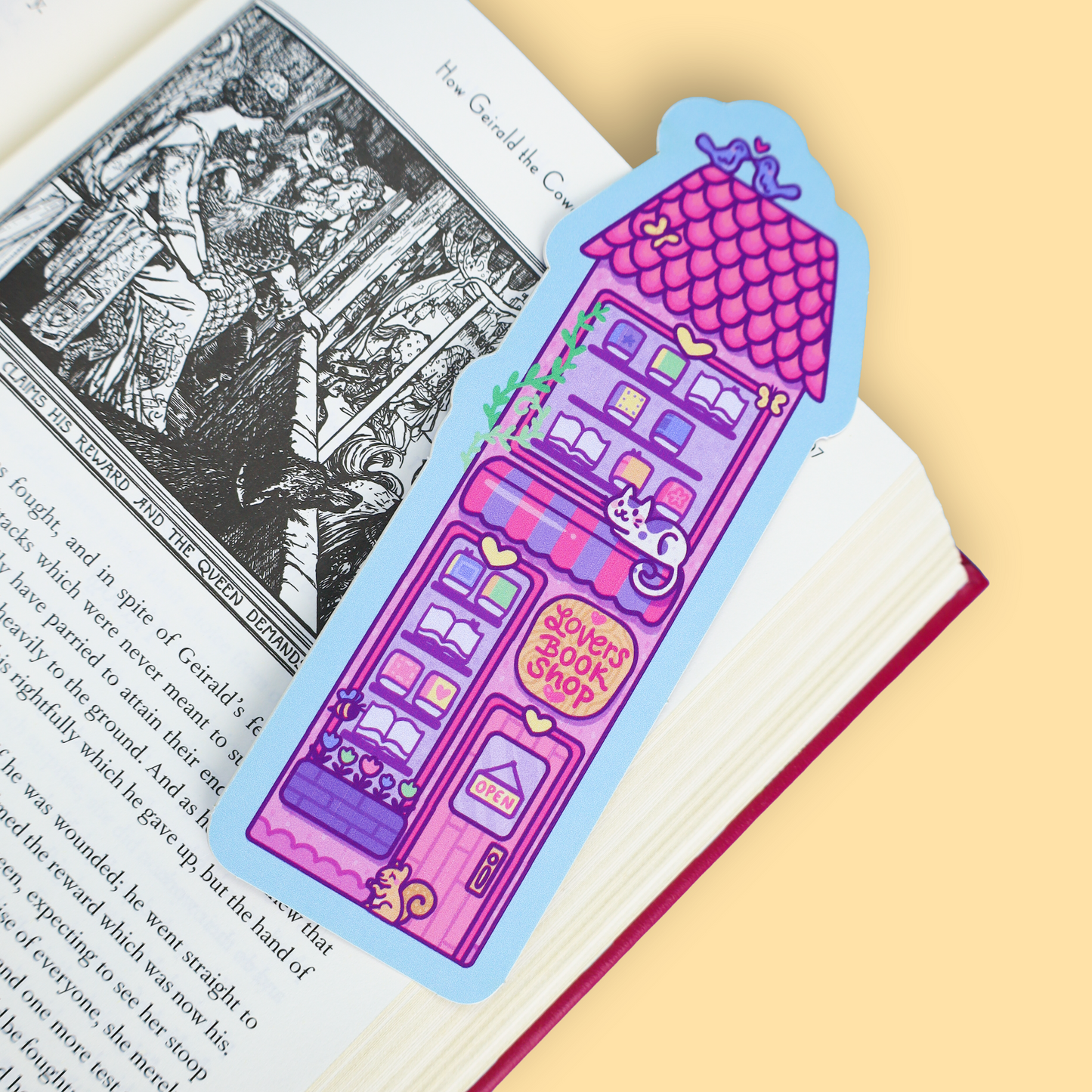 A colorful bookmark shaped like a pink house with a purple roof and the words 'Stories Book Shop' printed on it, placed on an open book page against a pale yellow background.