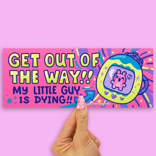 A hand with pink patterned nail polish holds a colorful rectangular sticker against a solid pink background. The sticker features a vibrant, retro-style design with the text 'GET OUT OF THE WAY!! MY LITTLE GUY IS DYING!!' in bold yellow and blue lettering, alongside a cartoon tamagotchi character inside a blue and yellow device.
