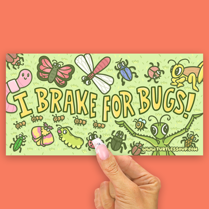 A rectangular printed card or sticker with a light green background and colorful cartoon bugs, held by a hand against a coral-orange backdrop. The card reads “I BRAKE FOR BUGS!” with “www.