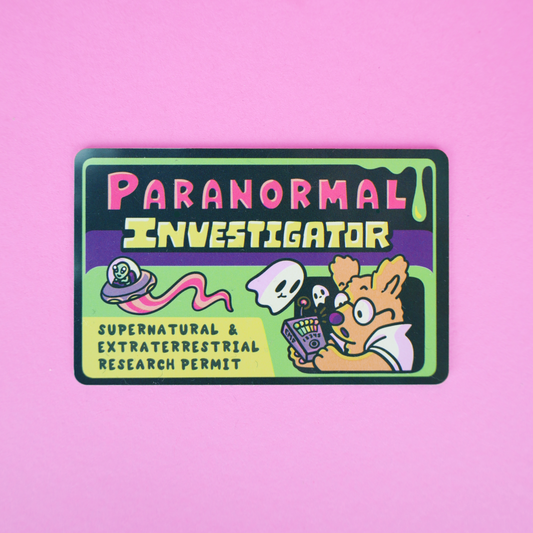 A rectangular sticker with rounded corners featuring a cartoon illustration and the text 'PARANORMAL INVESTIGATOR' and 'SUPERNATURAL & EXTRATERRESTRIAL RESEARCH PERMIT' on a bright pink background.