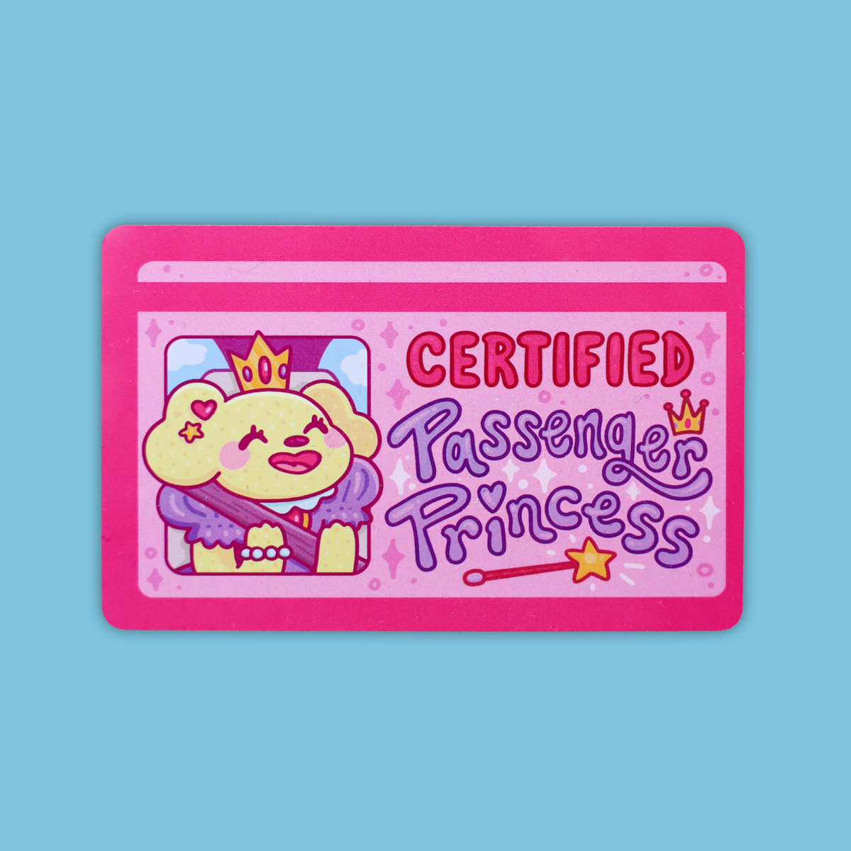 A pink rectangular sticker or card featuring a cartoon dog wearing a crown and purple outfit, with the text 'CERTIFIED Passenger Princess' on a light blue background.