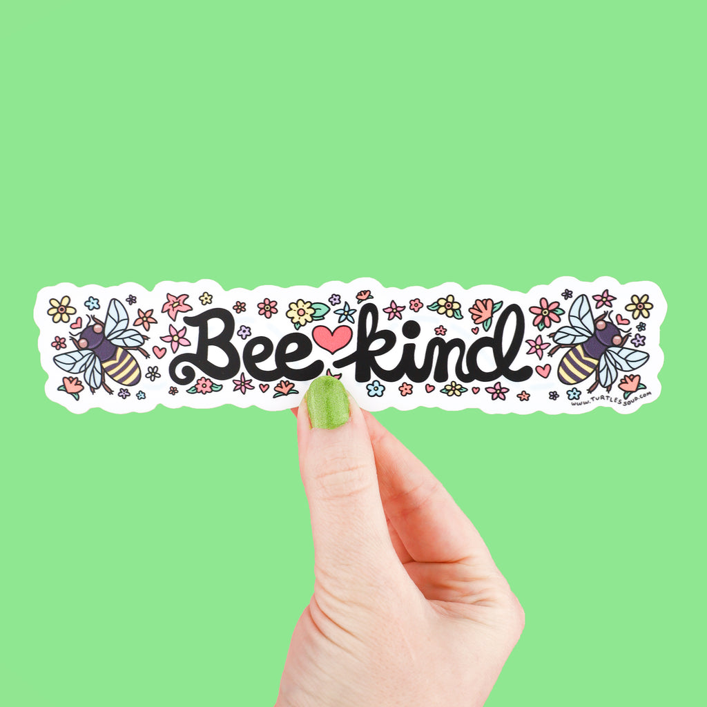 Long sticker with white background and colorful flowers. In the center is the text 'Bee Kind' and to its side is honeybees