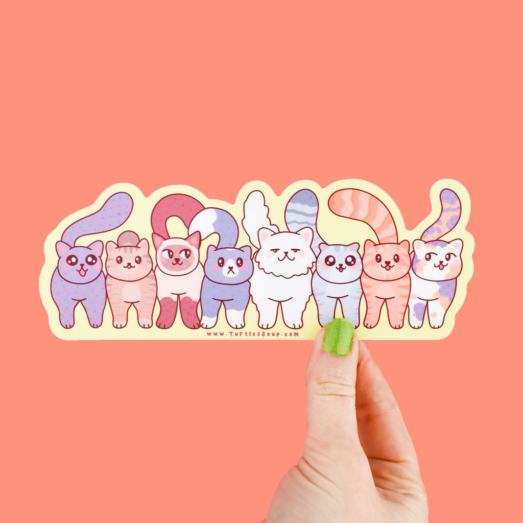 A long sticker featuring a group of cats standing together in a row, they are many shapes and colors of cats