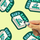 photo of a bird bam mahjong vinyl sticker being held against a yellow back drop