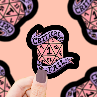 Sticker with a D20 die design and 'Critical Fail' text held by a hand against a patterned background.