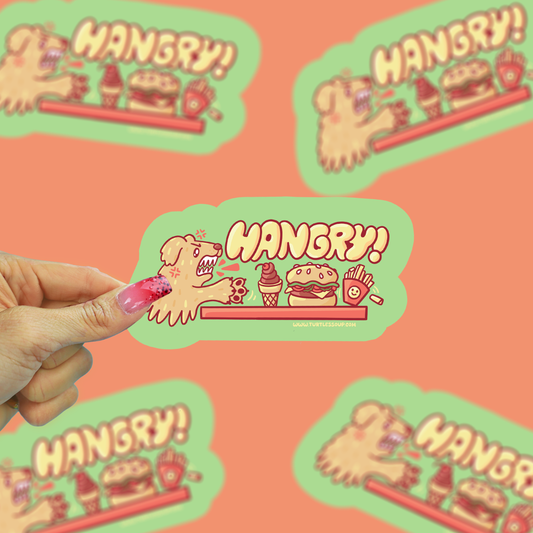 Hand holding a 'Hangry!' sticker with a cartoon dog and food items on an orange background.