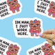 Sticker with bear character and text 'IDK MAN, I JUST WORK HERE.' held by a hand against a blue background.