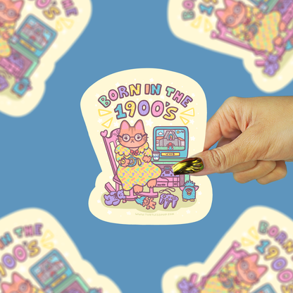 cat in a rocking chair surrounded by cute stuff from the 1990s being held against a blue background