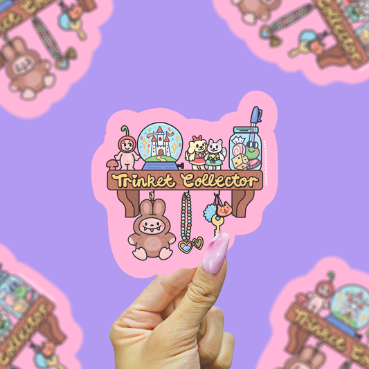 a vinyl sticker that says trinket collector of little trinkets on a shelf being held against a purple background.
