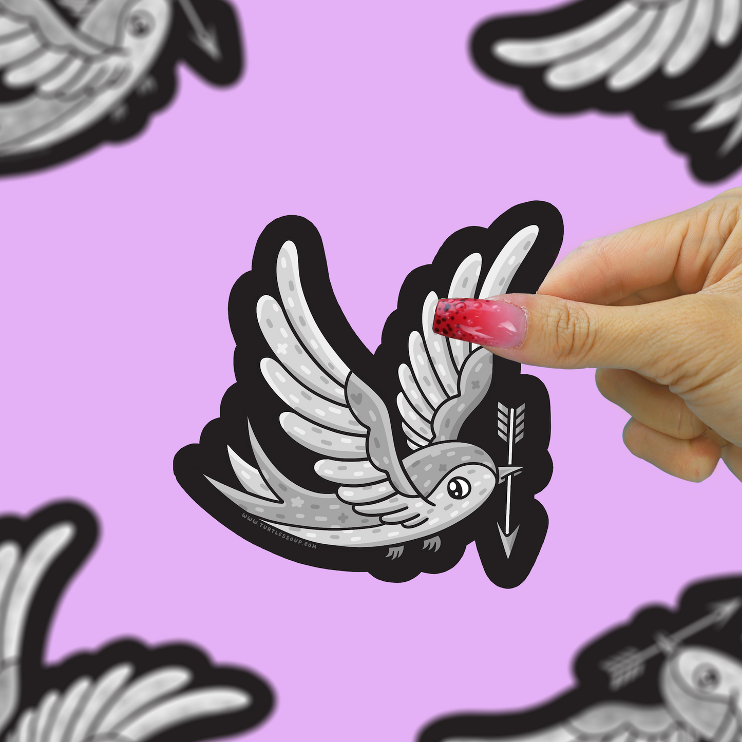 A hand with pink glittery nails holds a die-cut sticker of a white and gray dove holding an arrow with a black outline, set against a light purple background with other blurred stickers.