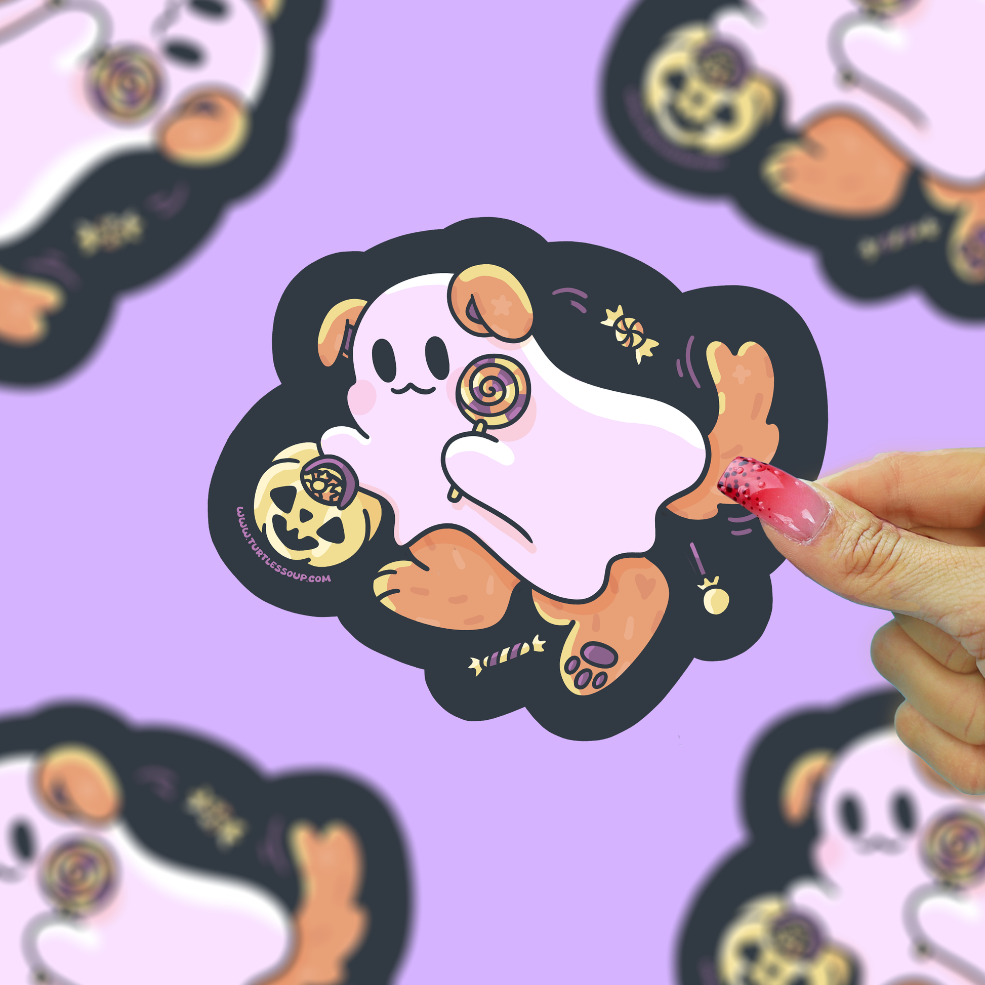 A hand with pink manicured nails holds a die-cut sticker featuring a cute cartoon ghost dog character. The sticker has a black outline, a pale pink body, brown paws and ears, and small gold Halloween-themed details, set against a light purple background with blurred duplicate sticker images.