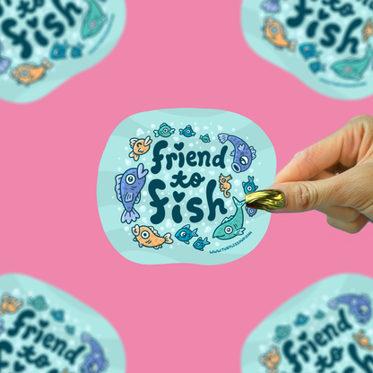 A hand holds a die-cut sticker featuring the phrase 'Friend to Fish' in dark teal lettering, surrounded by colorful cartoon fish on a light blue background. The sticker is shown against a bright pink background with other identical stickers partially visible around the edges.