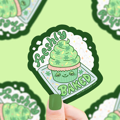 A very high cupcake with green frosting and leaf sprinkles. Text says "freshly baked"
