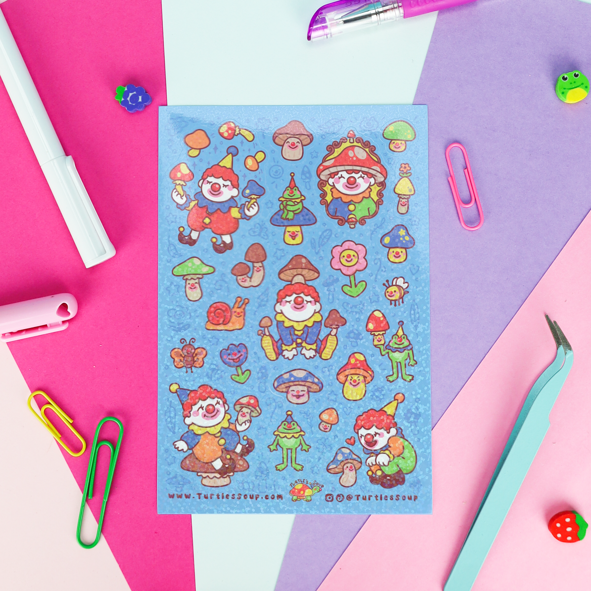 A sheet of colorful mushroom-themed stickers laid flat on a pastel paper background, surrounded by stationery props including paper clips, a pen, tweezers, and small decorative items.